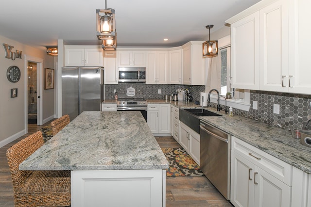 kitchen with white cabinets, a kitchen island, stainless steel appliances, and pendant lighting