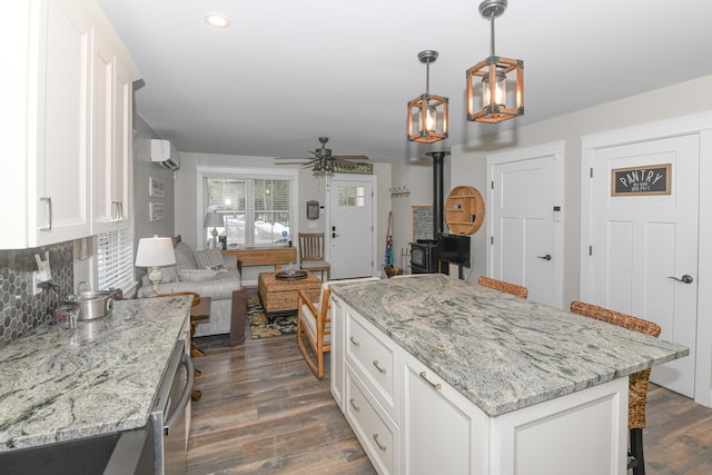 kitchen featuring ceiling fan, white cabinets, a kitchen bar, and pendant lighting