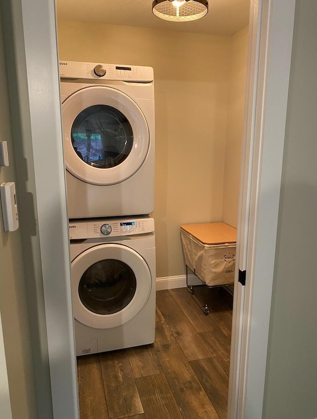 laundry area with dark hardwood / wood-style floors and stacked washer and clothes dryer