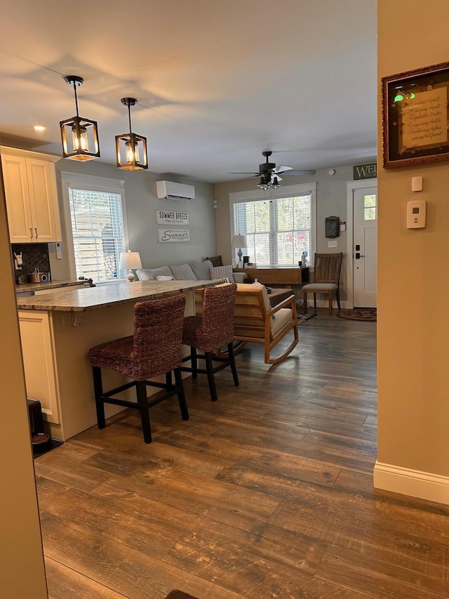 kitchen with white cabinetry, ceiling fan, dark hardwood / wood-style flooring, pendant lighting, and a breakfast bar