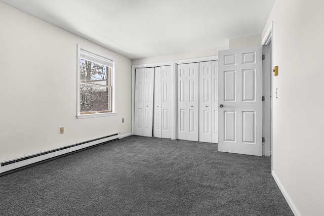 unfurnished bedroom with multiple closets, dark colored carpet, and a baseboard heating unit