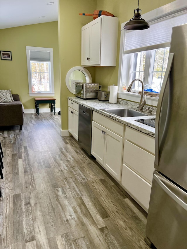 kitchen with white cabinetry, stainless steel fridge, dishwasher, pendant lighting, and sink