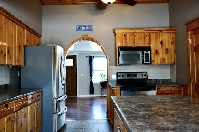 kitchen featuring decorative backsplash, dark tile patterned flooring, appliances with stainless steel finishes, and ceiling fan