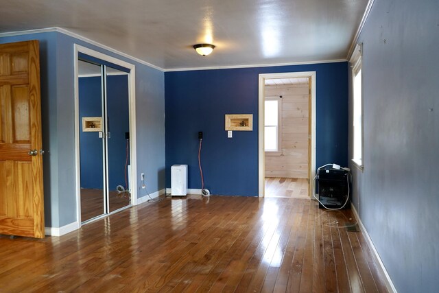 empty room featuring crown molding, hardwood / wood-style flooring, and heating unit