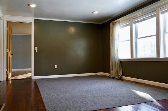 spare room featuring ornamental molding and dark hardwood / wood-style floors