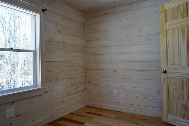 unfurnished room featuring light hardwood / wood-style floors and wooden walls