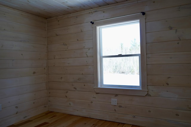 empty room with wooden ceiling, plenty of natural light, wood walls, and light wood-type flooring