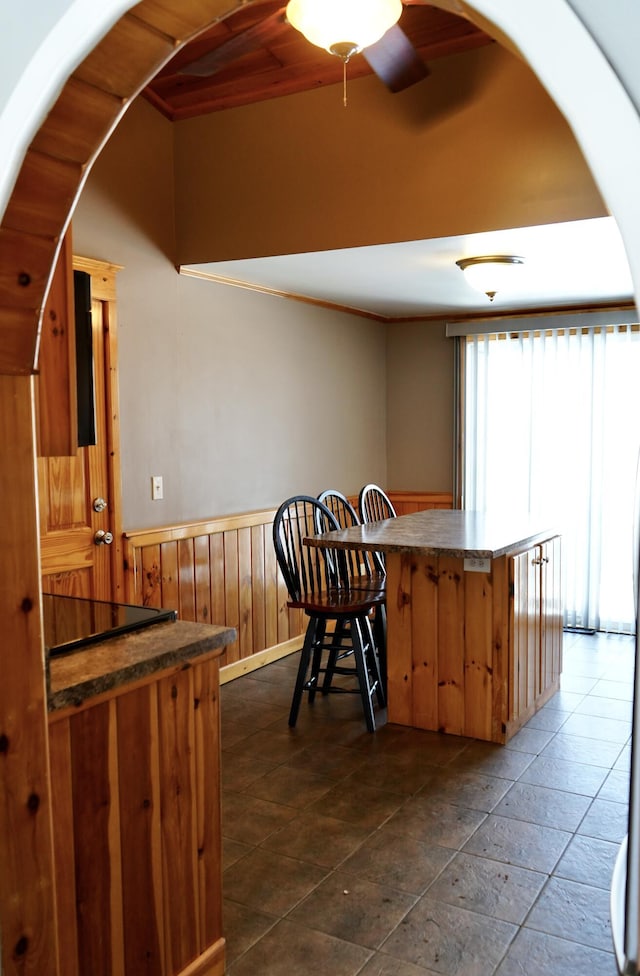 kitchen featuring ceiling fan, kitchen peninsula, and wooden walls