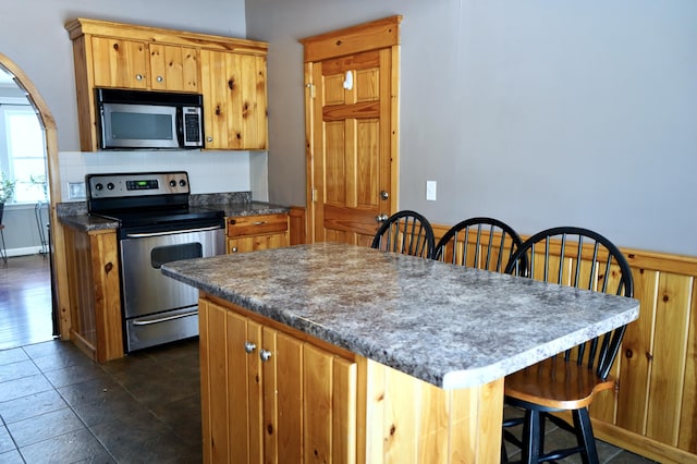 kitchen with backsplash, appliances with stainless steel finishes, and a kitchen breakfast bar