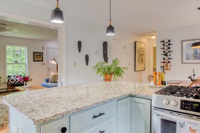 kitchen with ceiling fan, light stone countertops, pendant lighting, and stainless steel gas range oven