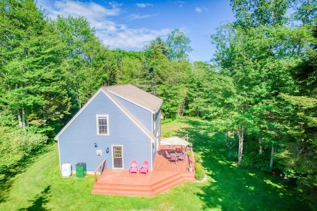 back of property featuring a wooden deck and a lawn