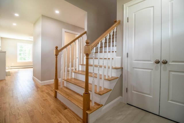 stairway with hardwood / wood-style flooring and a baseboard heating unit