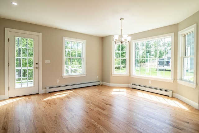 unfurnished dining area with light hardwood / wood-style floors, a wealth of natural light, a baseboard heating unit, and an inviting chandelier