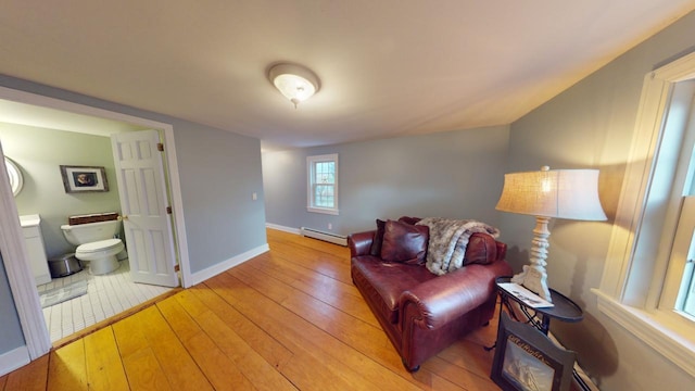 living room with baseboard heating and light hardwood / wood-style flooring