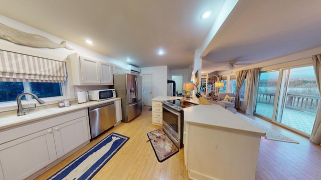 kitchen with light hardwood / wood-style flooring, ceiling fan, sink, white cabinetry, and stainless steel appliances