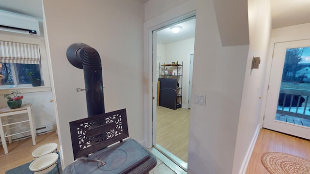 interior space with a baseboard heating unit, light wood-type flooring, and a wall mounted air conditioner