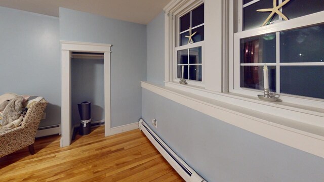 hall with light wood-type flooring and a baseboard heating unit