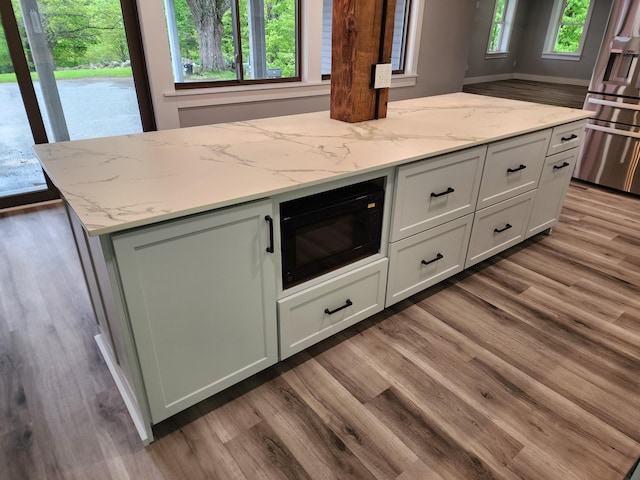 61 Hathaway Hill Rd, Livermore, ME 04253 - kitchen featuring black microwave, light wood-style flooring, stainless steel fridge, a center island, and light stone counters