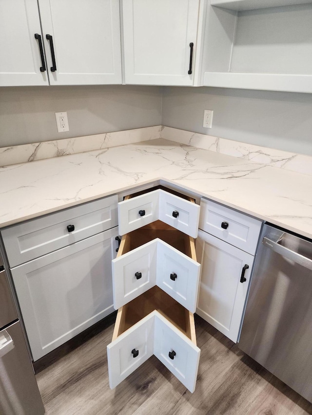 61 Hathaway Hill Rd, Livermore, ME 04253 - kitchen featuring stainless steel dishwasher, light wood-style floors, white cabinets, and light stone countertops