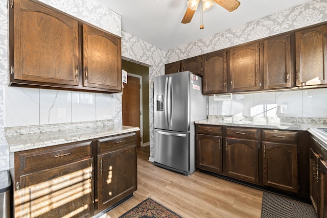 kitchen with light stone counters, ceiling fan, stainless steel fridge with ice dispenser, and light hardwood / wood-style flooring