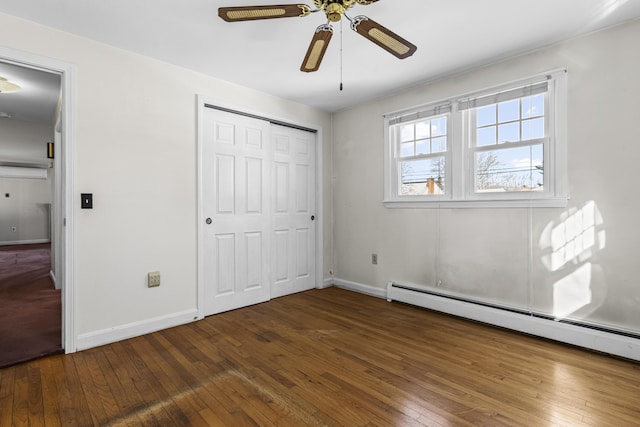 unfurnished bedroom with a baseboard heating unit, ceiling fan, dark hardwood / wood-style flooring, and a closet