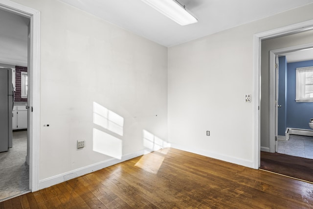 unfurnished room featuring baseboard heating and wood-type flooring