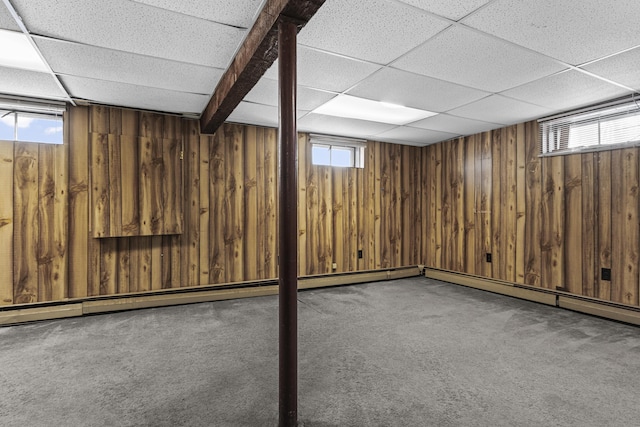 basement featuring a wealth of natural light, a paneled ceiling, and carpet flooring