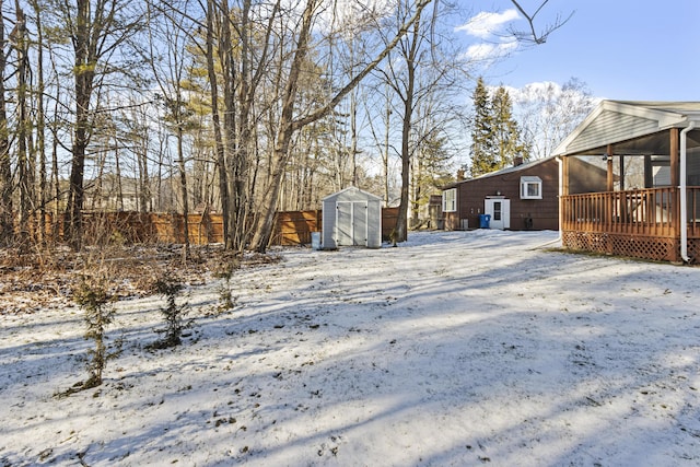 yard layered in snow featuring a shed and a wooden deck