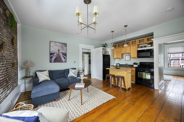 living room featuring dark hardwood / wood-style flooring, brick wall, and an inviting chandelier