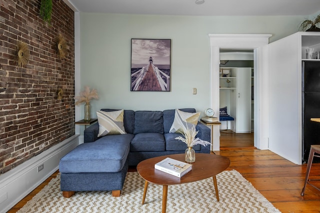 living room featuring brick wall and dark hardwood / wood-style flooring