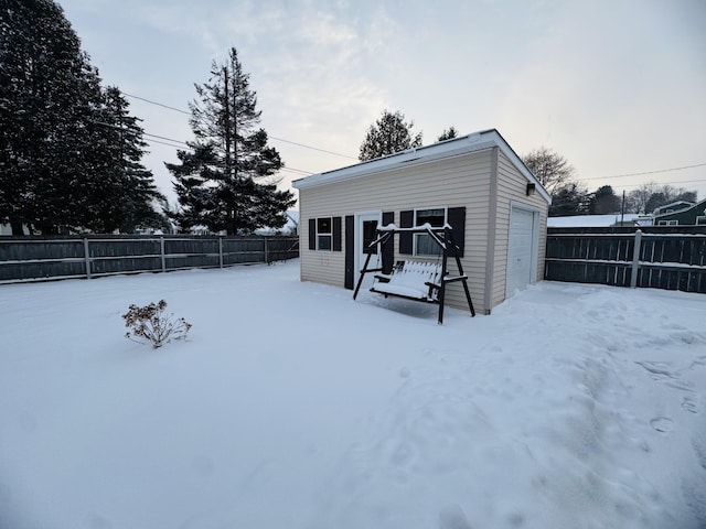 snow covered property featuring a garage and an outbuilding