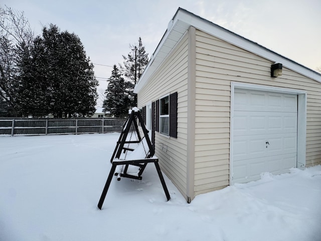 snow covered property with a garage and an outbuilding