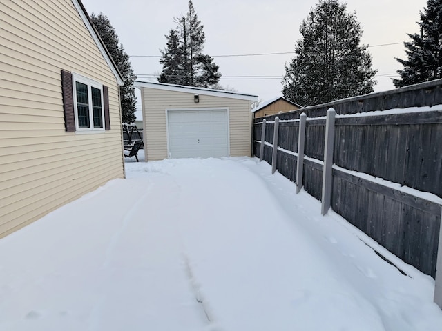 yard covered in snow featuring a garage and an outdoor structure