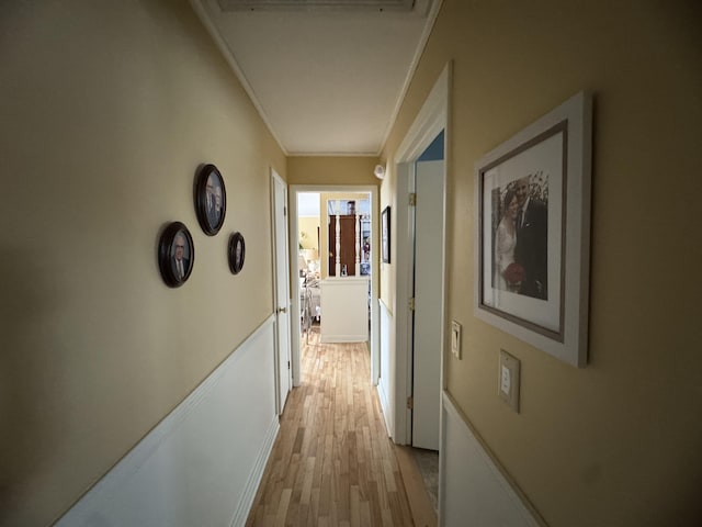 corridor featuring light wood-type flooring and crown molding