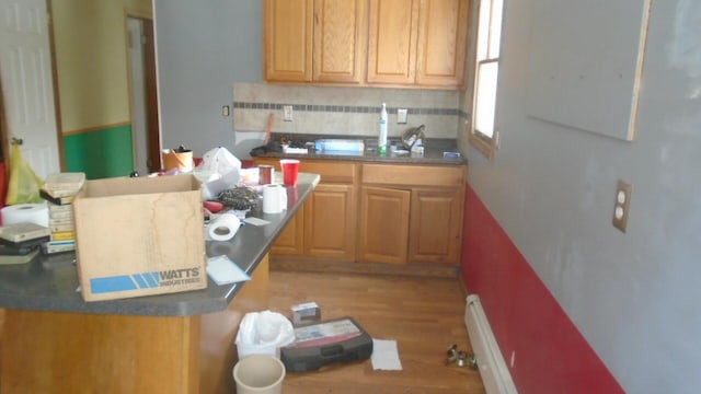 kitchen with light hardwood / wood-style floors, baseboard heating, and tasteful backsplash