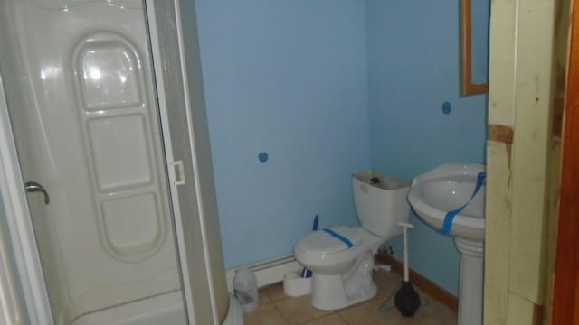 bathroom with toilet, a shower, tile patterned floors, and a baseboard radiator