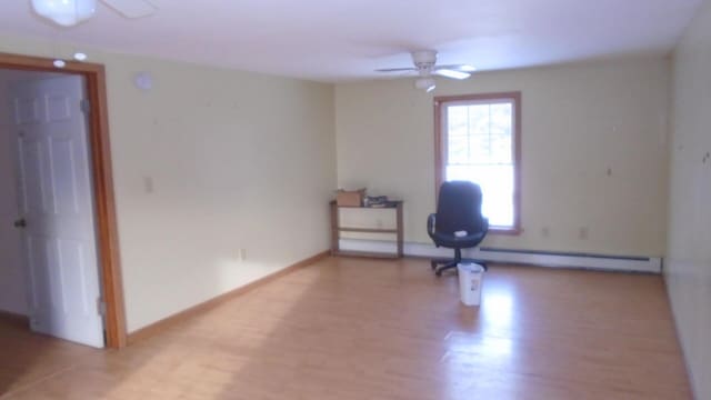 empty room featuring ceiling fan, a baseboard heating unit, and light hardwood / wood-style flooring