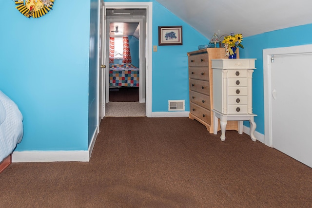 unfurnished bedroom with lofted ceiling and dark colored carpet