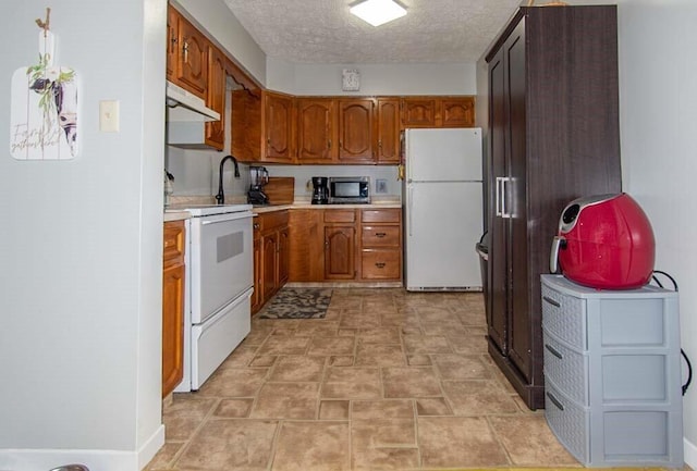 kitchen featuring sink, white appliances, and a textured ceiling