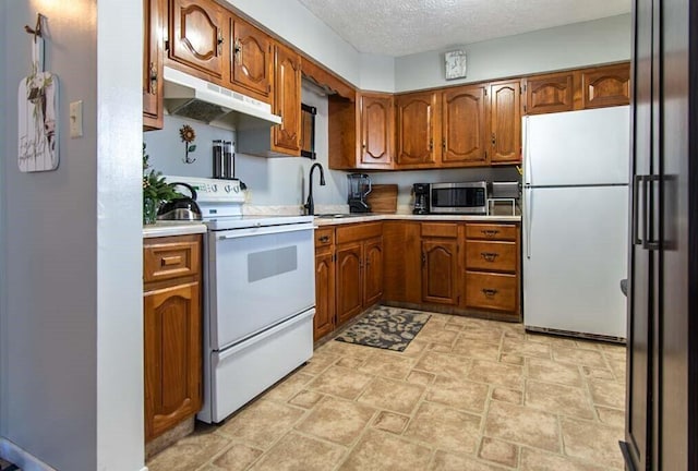 kitchen with sink, white appliances, and a textured ceiling