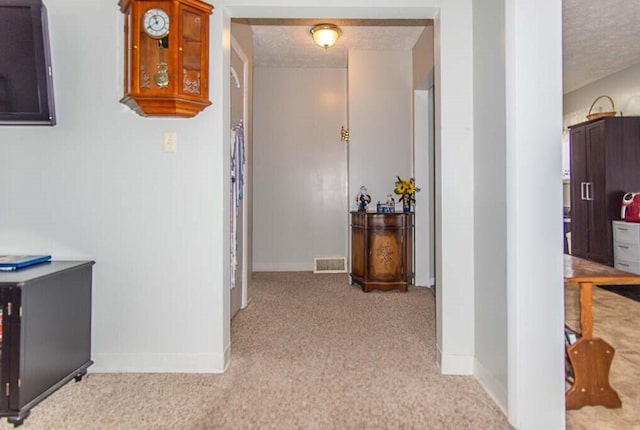 hallway with a textured ceiling and light colored carpet