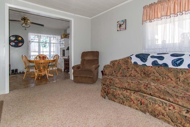 carpeted living room with ceiling fan and ornamental molding