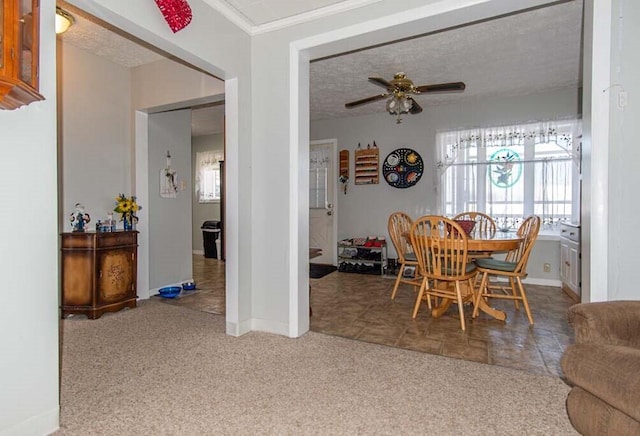 carpeted dining area with ceiling fan, a textured ceiling, and ornamental molding