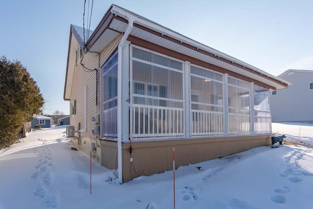 view of snowy exterior with a sunroom