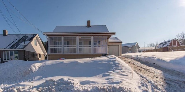 snow covered house featuring a sunroom