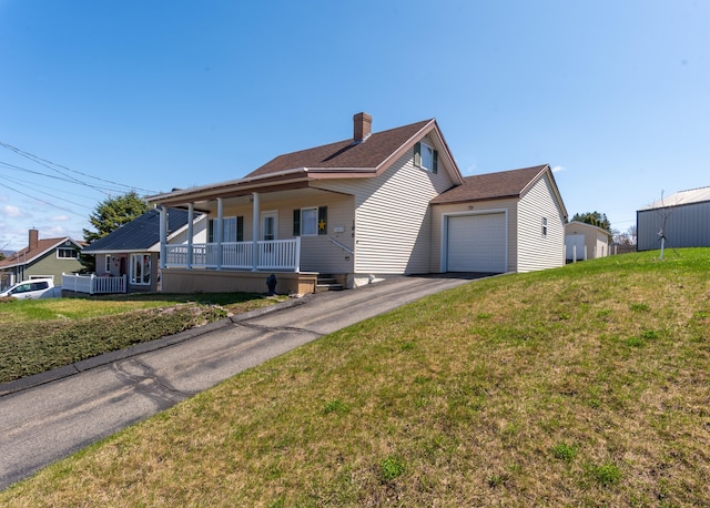 186 Mountain View Ave, Madawaska, ME 04756 - view of front facade with covered porch, asphalt driveway, a chimney, a front lawn, and a garage