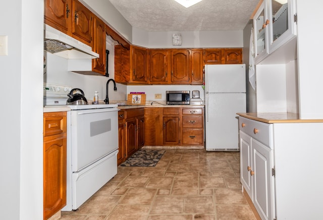 186 Mountain View Ave, Madawaska, ME 04756 - kitchen with white appliances, under cabinet range hood, brown cabinetry, light countertops, and stone finish flooring