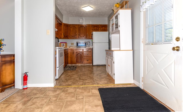186 Mountain View Ave, Madawaska, ME 04756 - kitchen featuring white appliances, baseboards, brown cabinetry, light countertops, and light stone finish floors