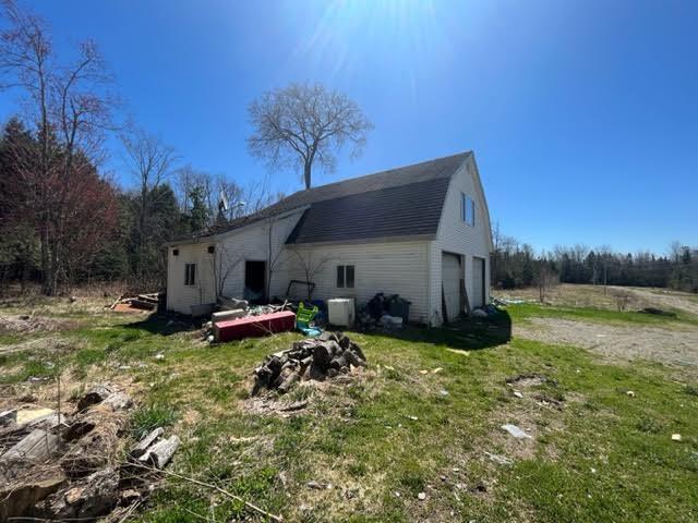 98 White Schoolhouse Rd, Corinth, ME 04427 - back of property with central AC unit, dirt driveway, and an attached garage