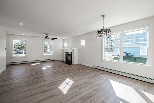 unfurnished living room with baseboard heating, wood-type flooring, and a premium fireplace